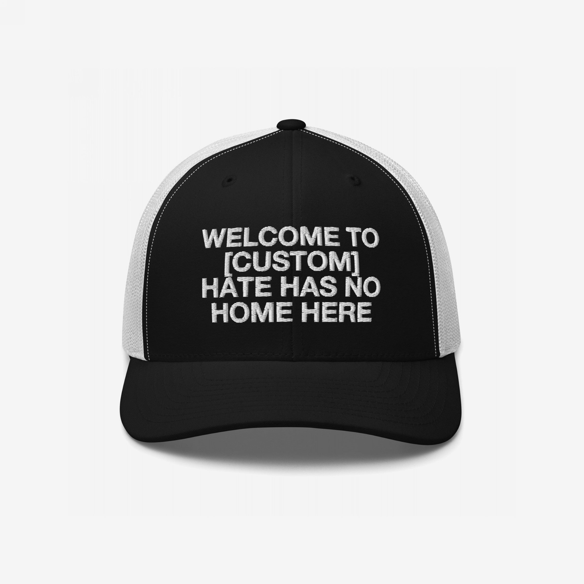 Custom Hate Has No Home Here Trucker Hat with a black front and white mesh back, featuring an embroidered message promoting community values and inclusion.