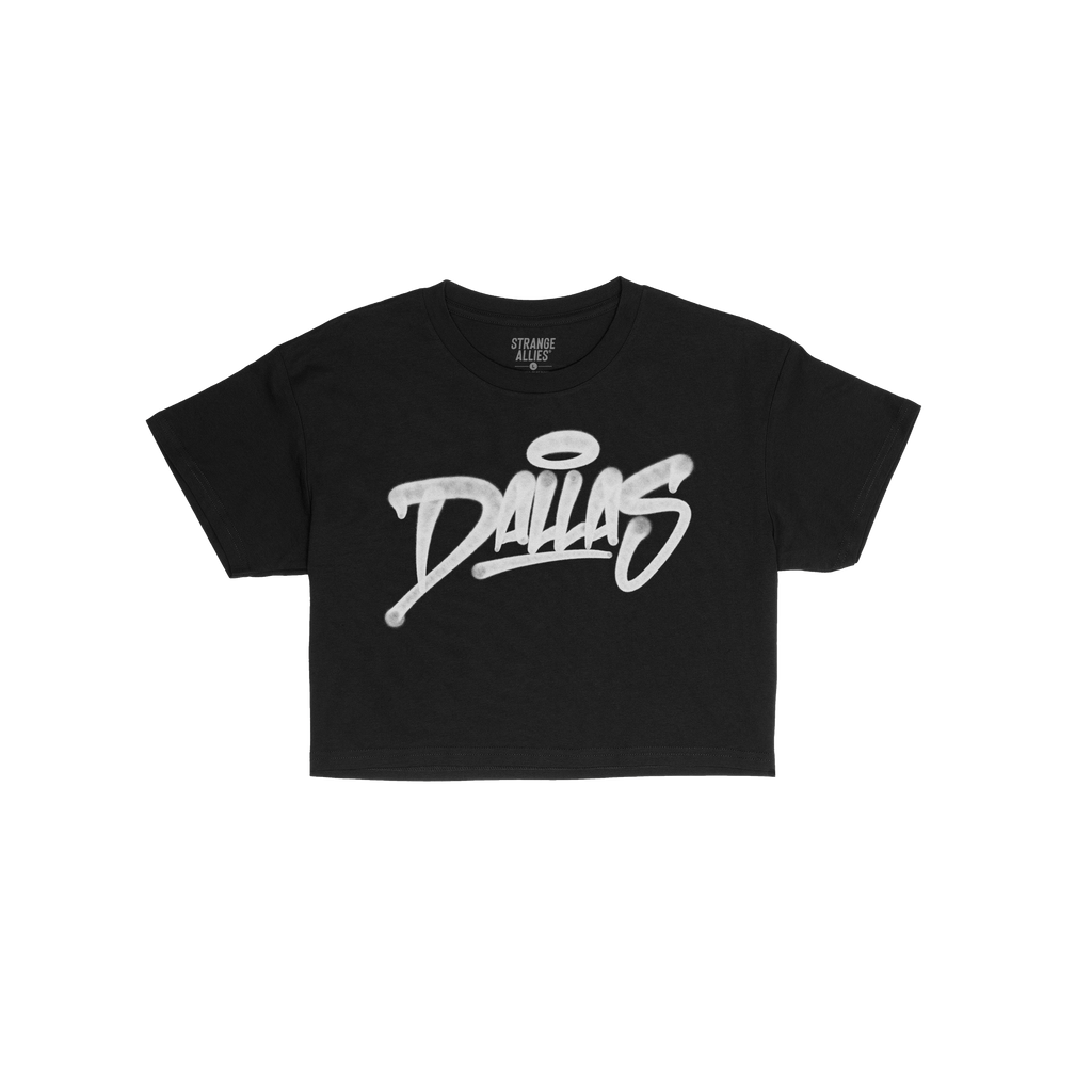 The Dallas Handstyle Women's Baby Tee displays a bold, white graffiti-style Dallas with a halo, on a black T-shirt, embodying