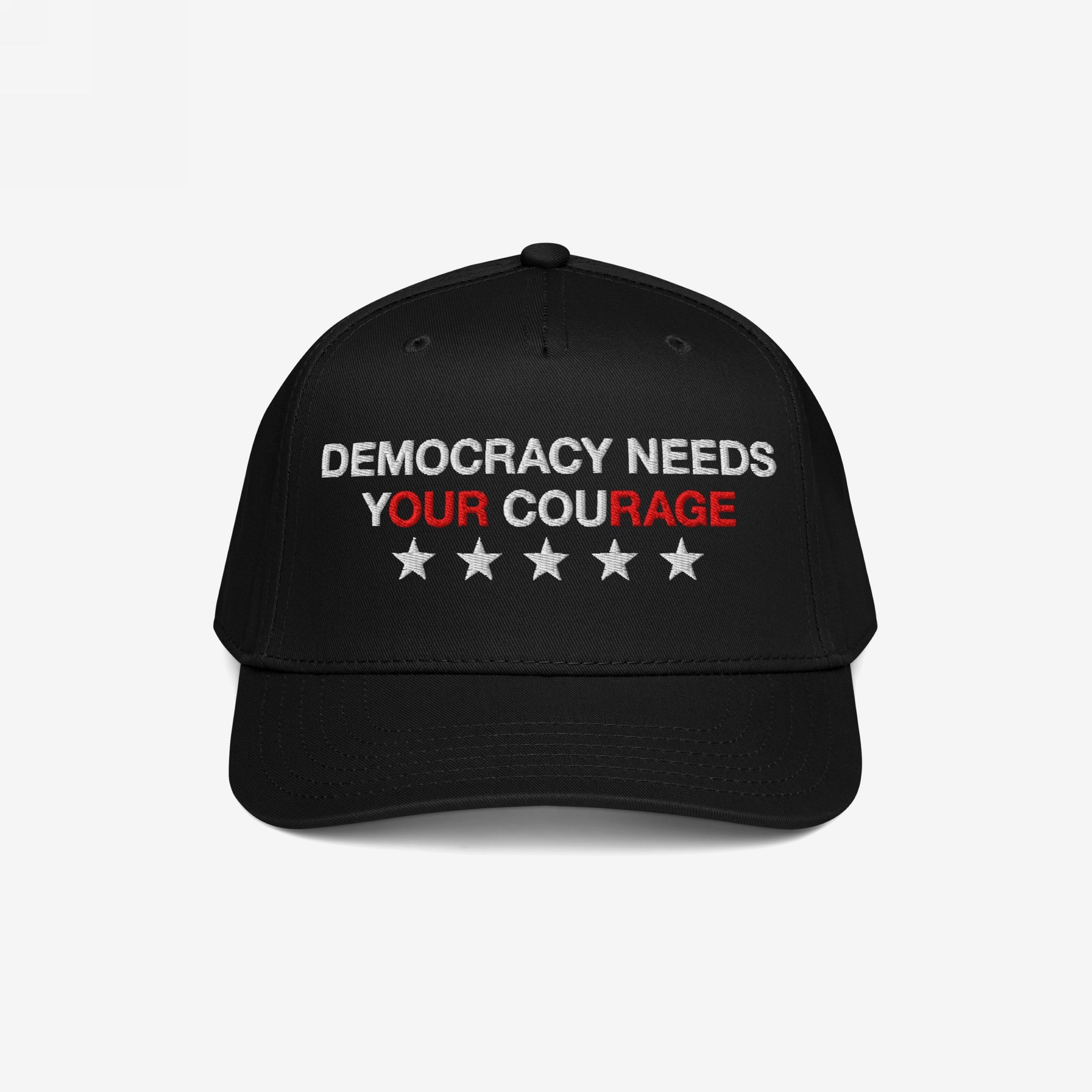 Democracy Hat: Black baseball-style cap featuring DEMOCRACY NEEDS YOUR COURAGE with YOUR COURAGE in red and five white stars, symbolizing a stance against authoritarianism and support for equality.