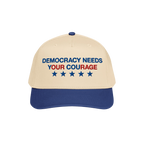 Two-tone Democracy Hat with beige front, blue bill. Embroidered “DEMOCRACY NEEDS YOUR COURAGE” in blue and red, with five