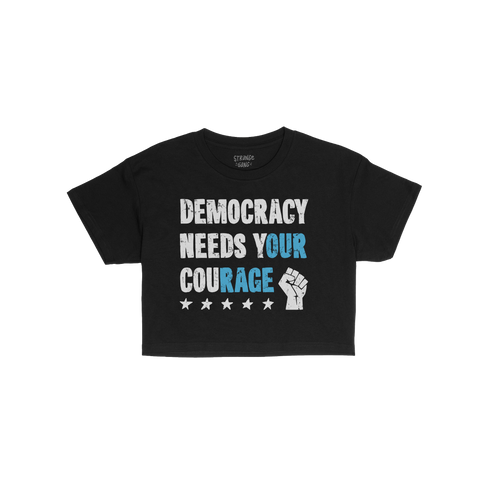 Black Democracy Women's Baby Tee with distressed slogan “DEMOCRACY NEEDS YOUR COURAGE,” highlighting “YOUR COURAGE” i