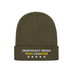 Olive-green knit Democracy Hat with folded cuff, featuring DEMOCRACY NEEDS YOUR COURAGE embroidered in white and yellow, and 