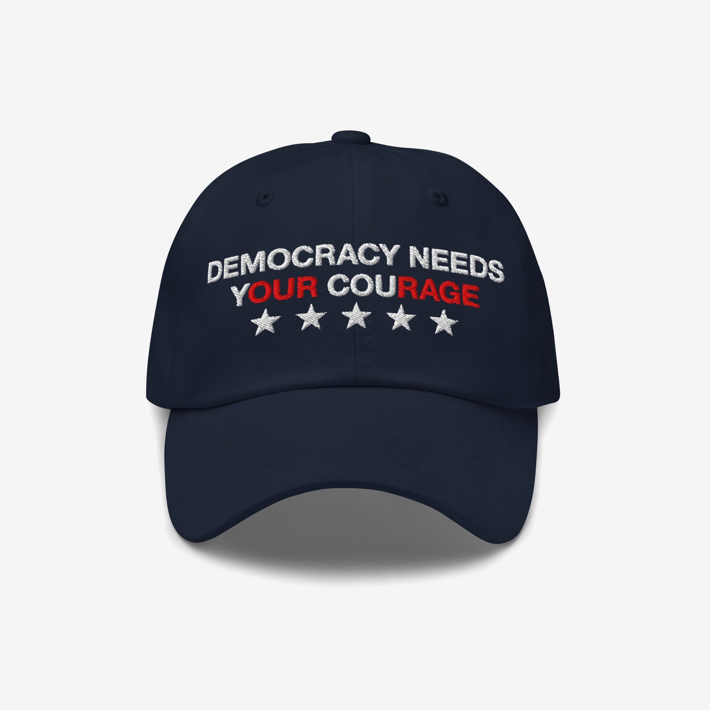 Navy blue Democracy Hat with “DEMOCRACY NEEDS YOUR COURAGE” embroidered on the front, highlighting YOUR COURAGE in red, complemented by five stars below. Ideal for showcasing anti-fascist values.