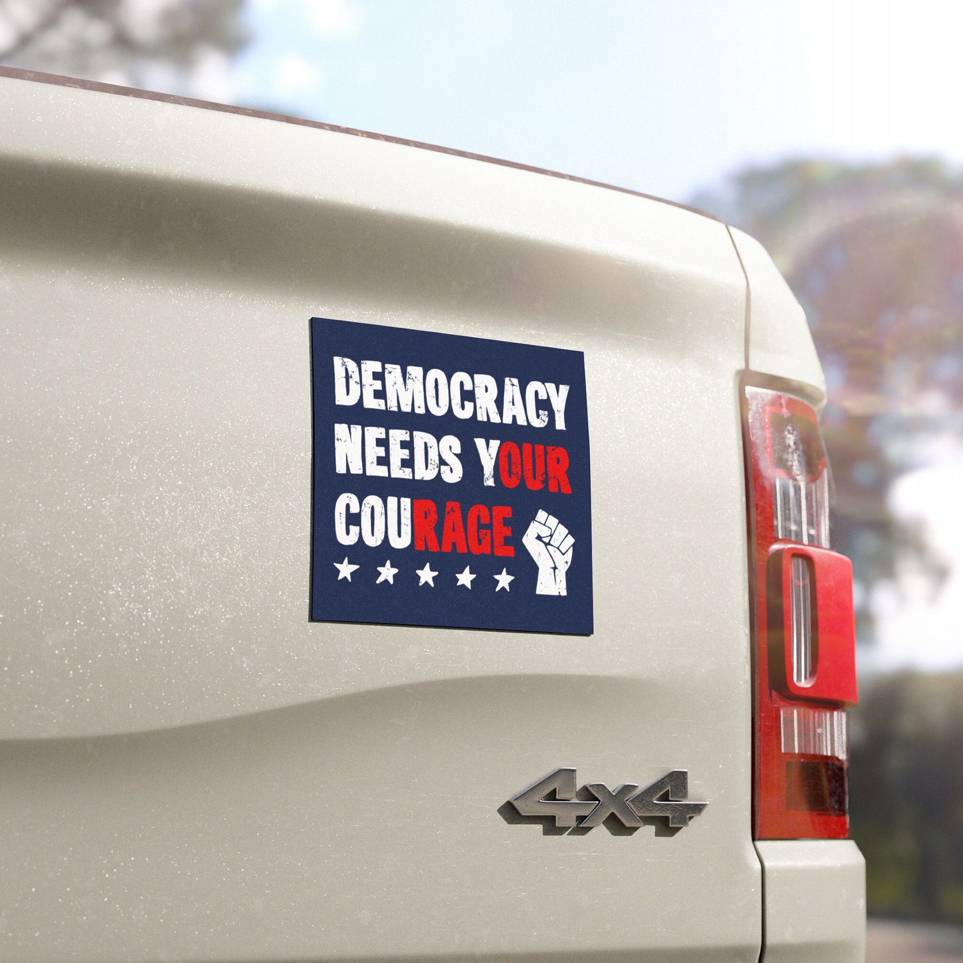 Democracy Sticker & Magnet on a white 4x4 tailgate, featuring DEMOCRACY NEEDS YOUR COURAGE with a clenched fist and stars, symbolizing progressive action against authoritarianism.