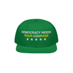 Green Democracy Hat with block letters “DEMOCRACY NEEDS YOUR COURAGE,” highlighting “YOUR COURAGE” in yellow. Feature
