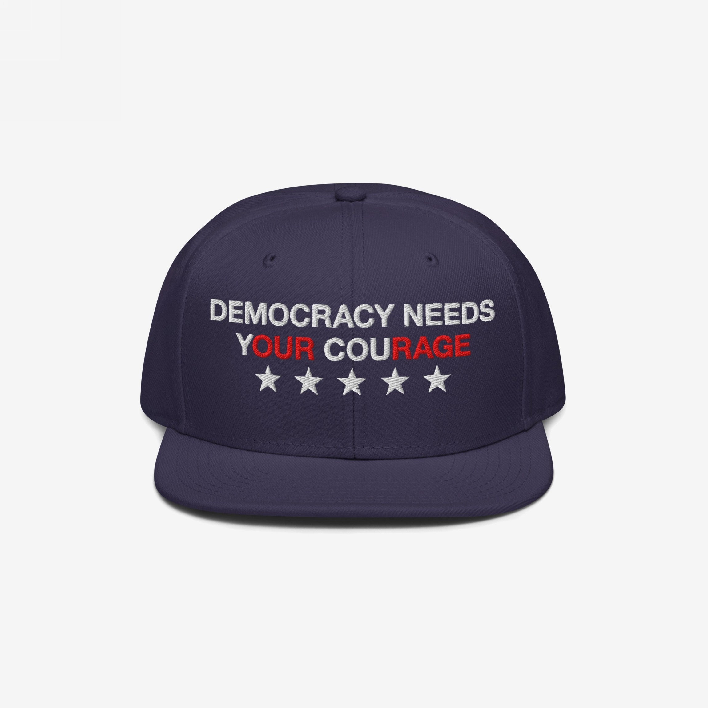 Navy-blue Democracy Hat with flat brim, embroidered with “Democracy Needs Your Courage” and stars, representing a bold anti-fascist statement. Ideal for expressing values in everyday settings.