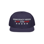 Navy-blue Democracy Hat with flat brim, embroidered with “Democracy Needs Your Courage” and stars, representing a bold an