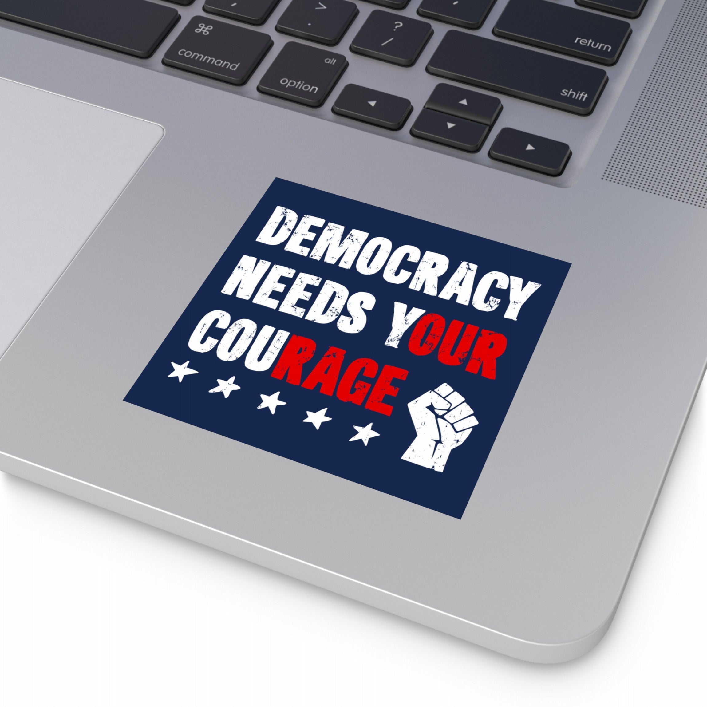 Democracy Sticker & Magnet on a laptop palm rest, featuring a distressed-style message emphasizing OUR RAGE in red, with stars and a raised fist icon, symbolizing resistance against authoritarianism.