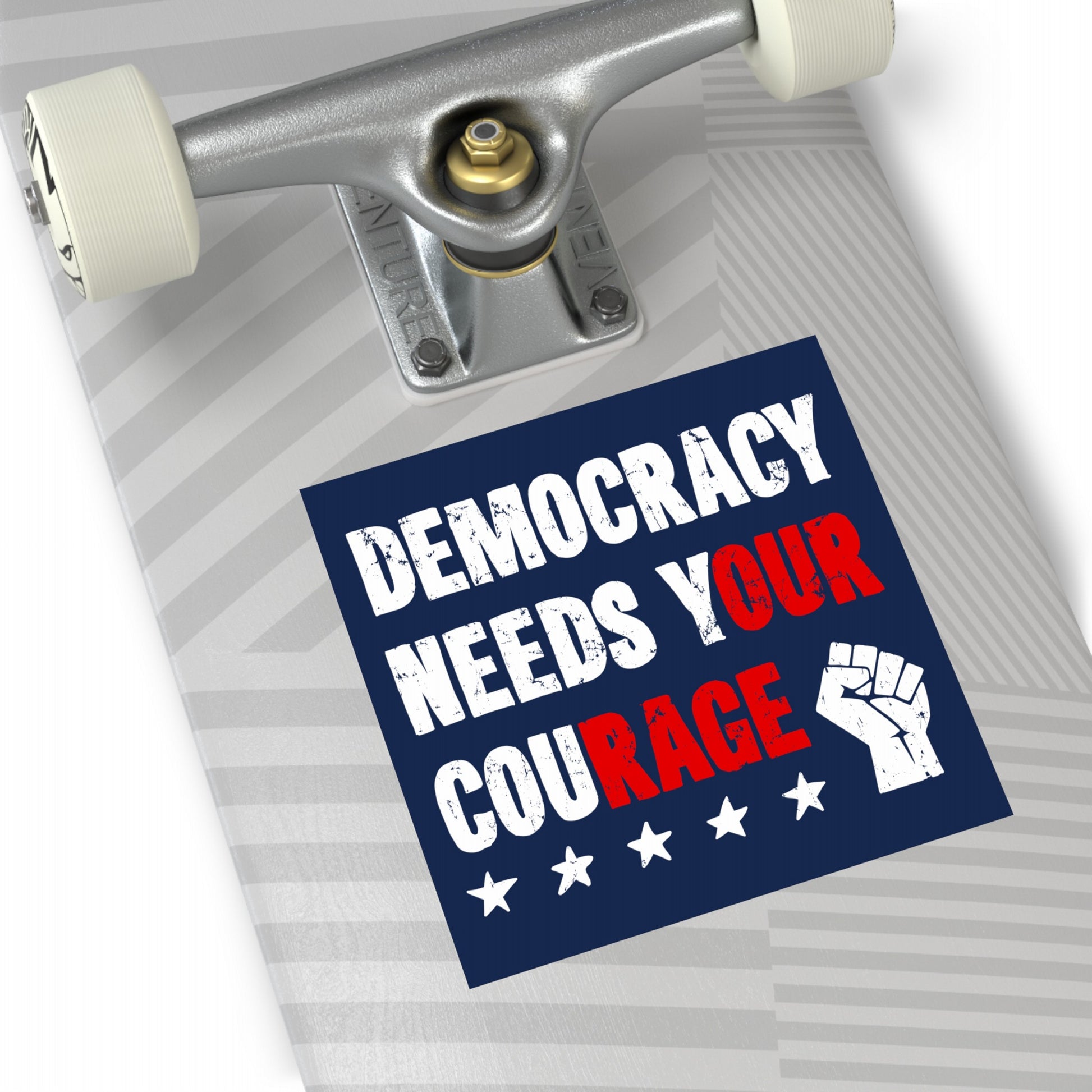 Skateboard deck with a Democracy Sticker & Magnet featuring bold text DEMOCRACY NEEDS YOUR COURAGE, white stars, and a fist icon, emphasizing civic action and resistance themes.