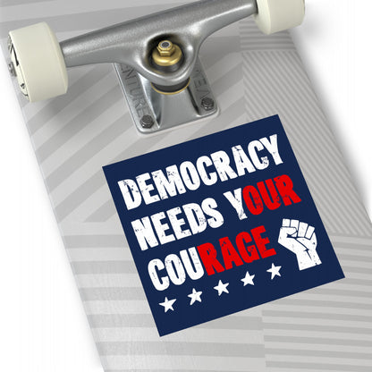 Skateboard deck with a Democracy Sticker & Magnet featuring bold text DEMOCRACY NEEDS YOUR COURAGE, white stars, and a fist icon, emphasizing civic action and resistance themes.