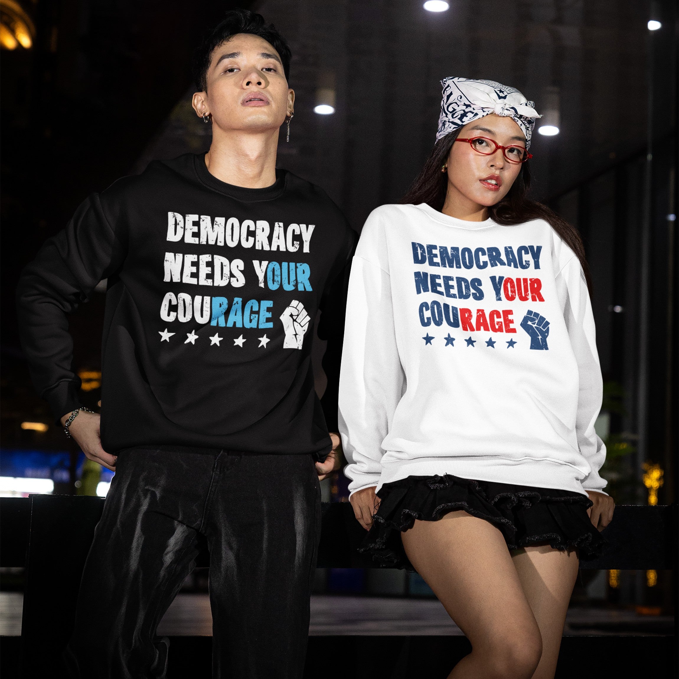 Two young adults wear Democracy Shirt sweatshirts featuring “Democracy Needs Your Courage slogan. They embody a bold, protest-driven style, reflecting a commitment to activism and equality.