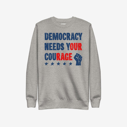 Democracy Hoodie & Sweatshirt featuring a distressed slogan DEMOCRACY NEEDS YOUR COURAGE with stars and a raised fist icon, embodying protest and resistance in bold red and blue graphics.