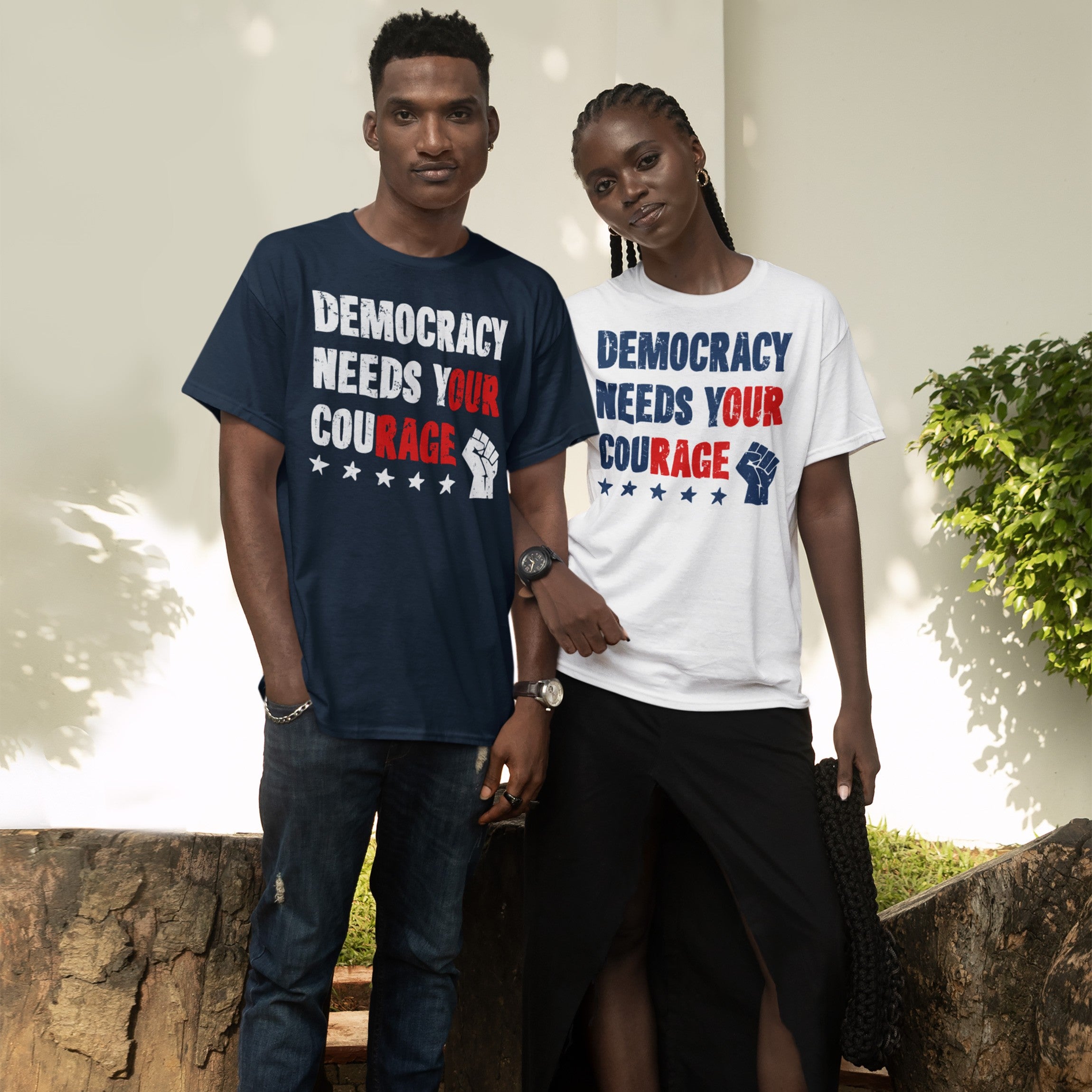 Two people wear Democracy Shirt, featuring bold Democracy Needs Your Courage text with a raised fist and stars, symbolizing resistance and empowerment. Available in various styles for activists.