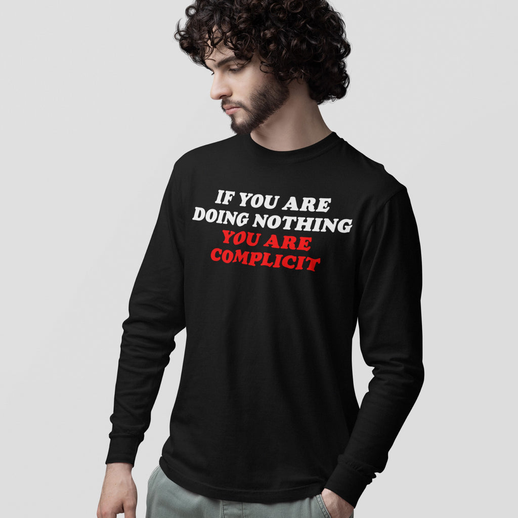 Young man with curly hair wears a Don't Be Complicit T-shirt, featuring bold protest slogan, standing against a plain background, embodying activism-focused style.