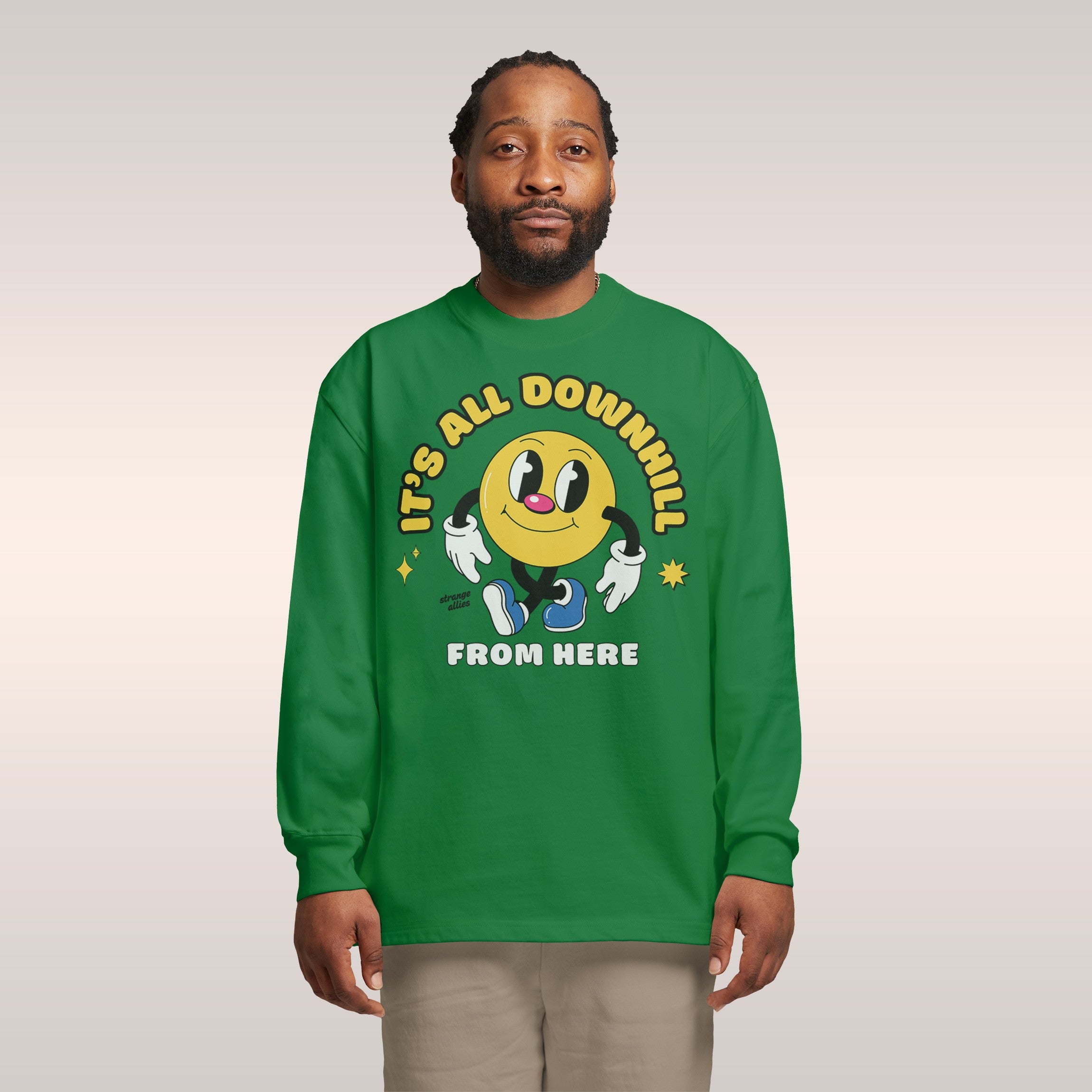 A person wears the Downhill Shirt showcasing a smiley-face character with text IT’S ALL DOWNHILL FROM HERE, embodying playf