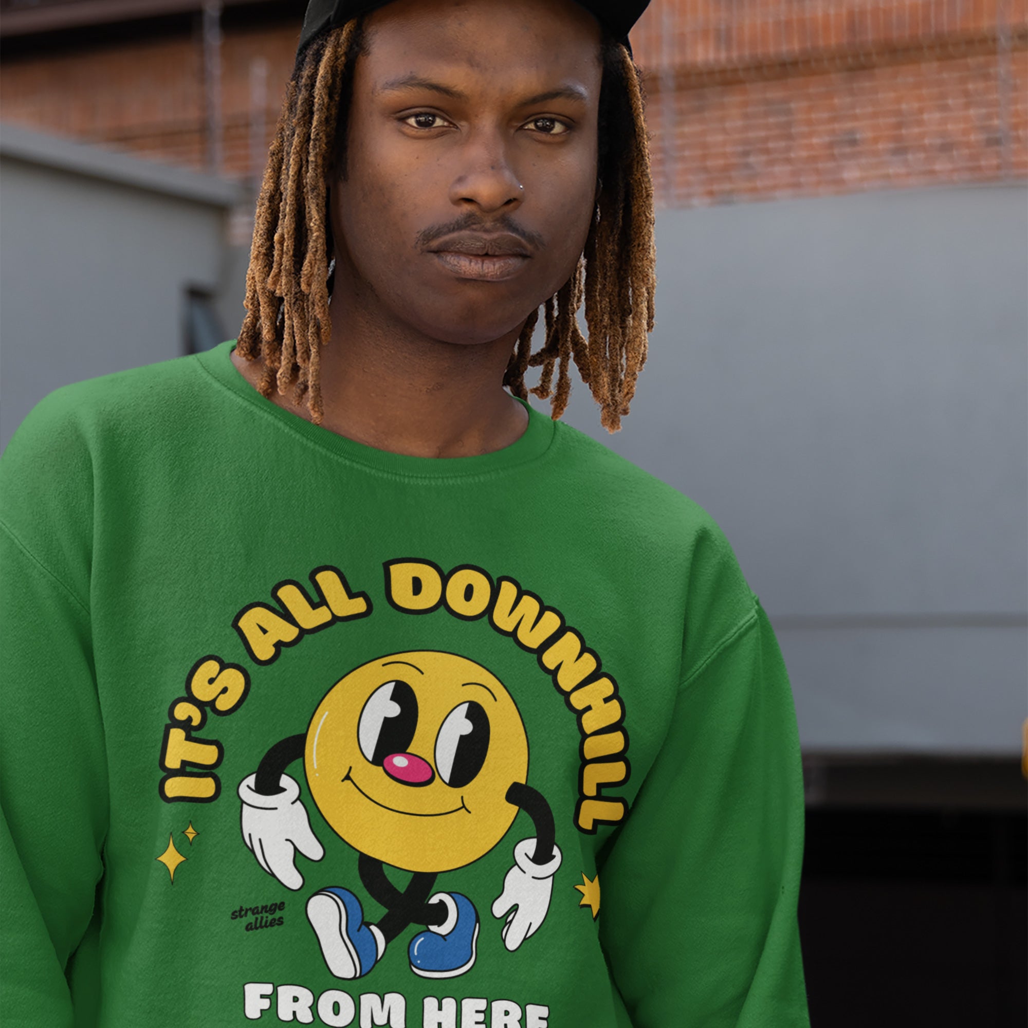 Young person in a bright green Downhill Shirt featuring a yellow smiley-face character with a playful slogan, embodying a cheeky, laid-back attitude. Ideal for embracing life’s twists with humor and ease.