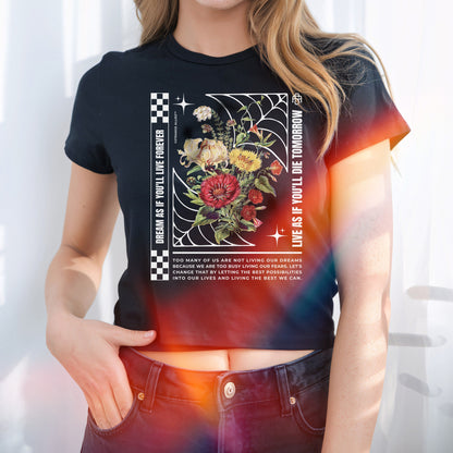 The Dreams Women's Baby Tee features a vibrant floral graphic within a web-like frame, checkerboard accents, and an inspirational quote, capturing bold, expressive style with existential flair.