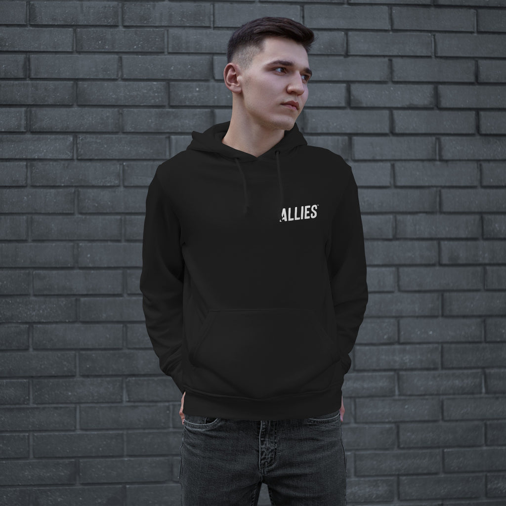 Young man in a black Dreams hoodie with ALLIES logo, embodying ambition and resilience. The hoodie features a front pouch pocket, reflecting defiance and determination. Perfect for those courageously chasing dreams.