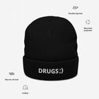 Black cuffed knit beanie with DRUGS ;) embroidered in white, featuring narrow-rib, double-layered recycled polyester knit, highlighting bold, ironic design with minimalist flair.