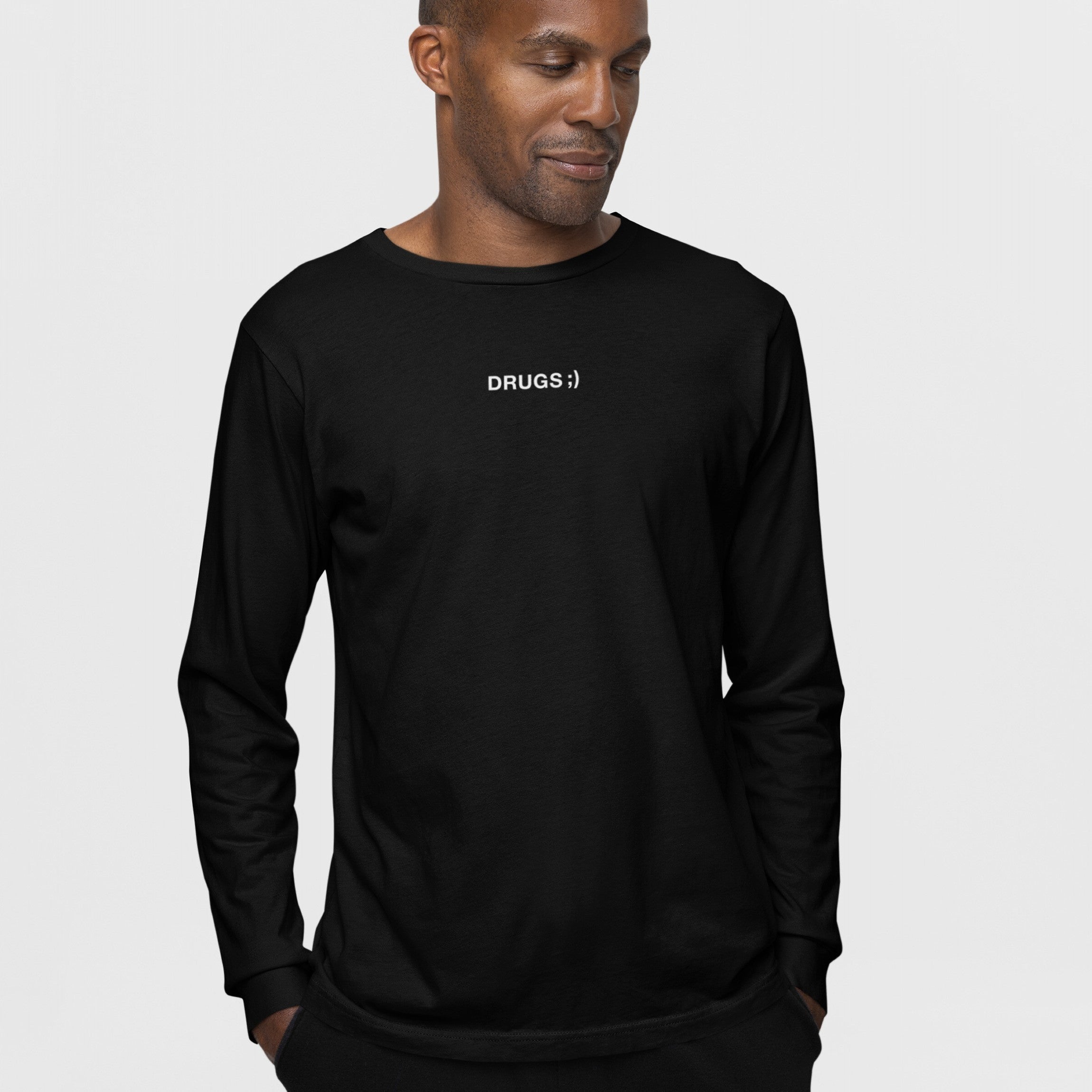 Drugs T-shirt featuring a minimalist design with DRUGS ;) in white text on a Black man's plain black long-sleeve shirt, embodying bold, unapologetic style.