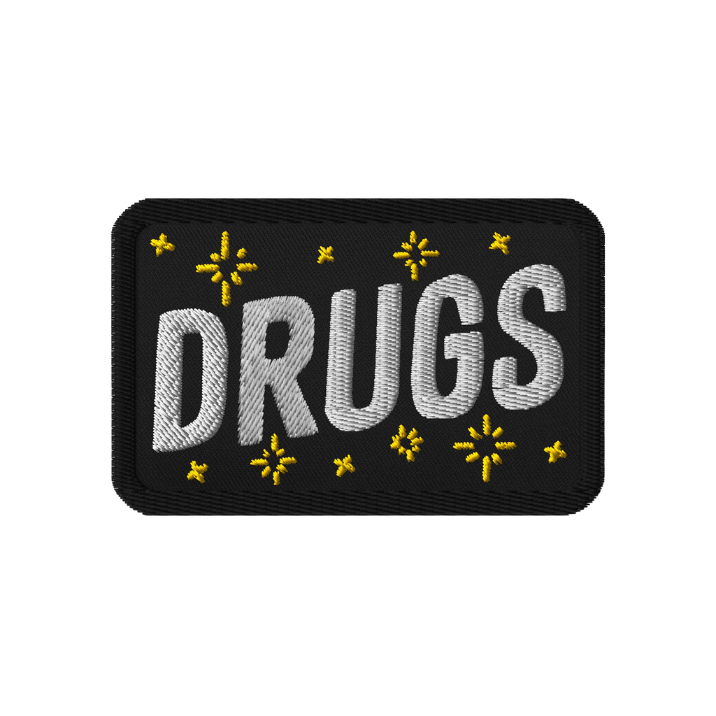 Drugs Patch featuring DRUGS in bold white stitching, adorned with small yellow star-like accents on black fabric. Perfect for