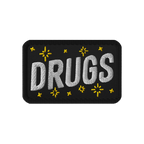 Drugs Patch featuring DRUGS in bold white stitching, adorned with small yellow star-like accents on black fabric. Perfect for
