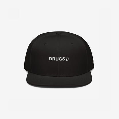 Black flat-brim snapback cap with DRUGS ;) embroidered in white, offering bold, edgy style. Ideal for making a statement, this hat aligns with the store's ethos of supporting equality and diversity.
