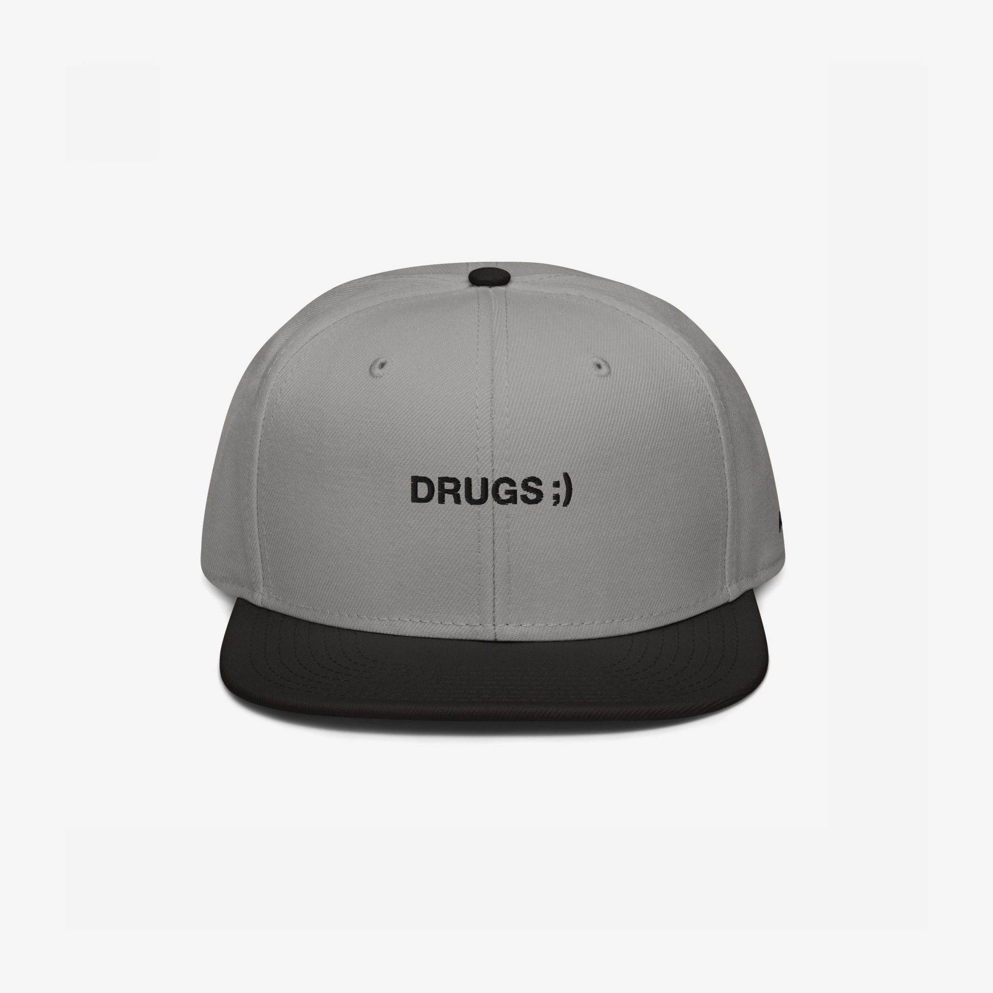 Two-tone snapback cap titled Drugs Hat with a light gray crown and black brim, featuring DRUGS ;) embroidered on the front, encapsulating a bold, ironic statement.