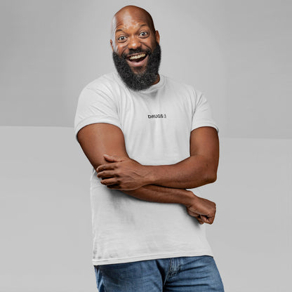 A smiling bald man models the Drugs T-shirt, featuring DRUGS ;) on the chest in black. He wears it casually with blue jeans, embodying the tee's bold, unapologetic message.
