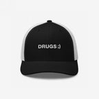 Drugs Hat: A black trucker cap with white mesh back, featuring DRUGS ;) embroidered in white sans-serif font, blending minimalist style with bold, ironic messaging.