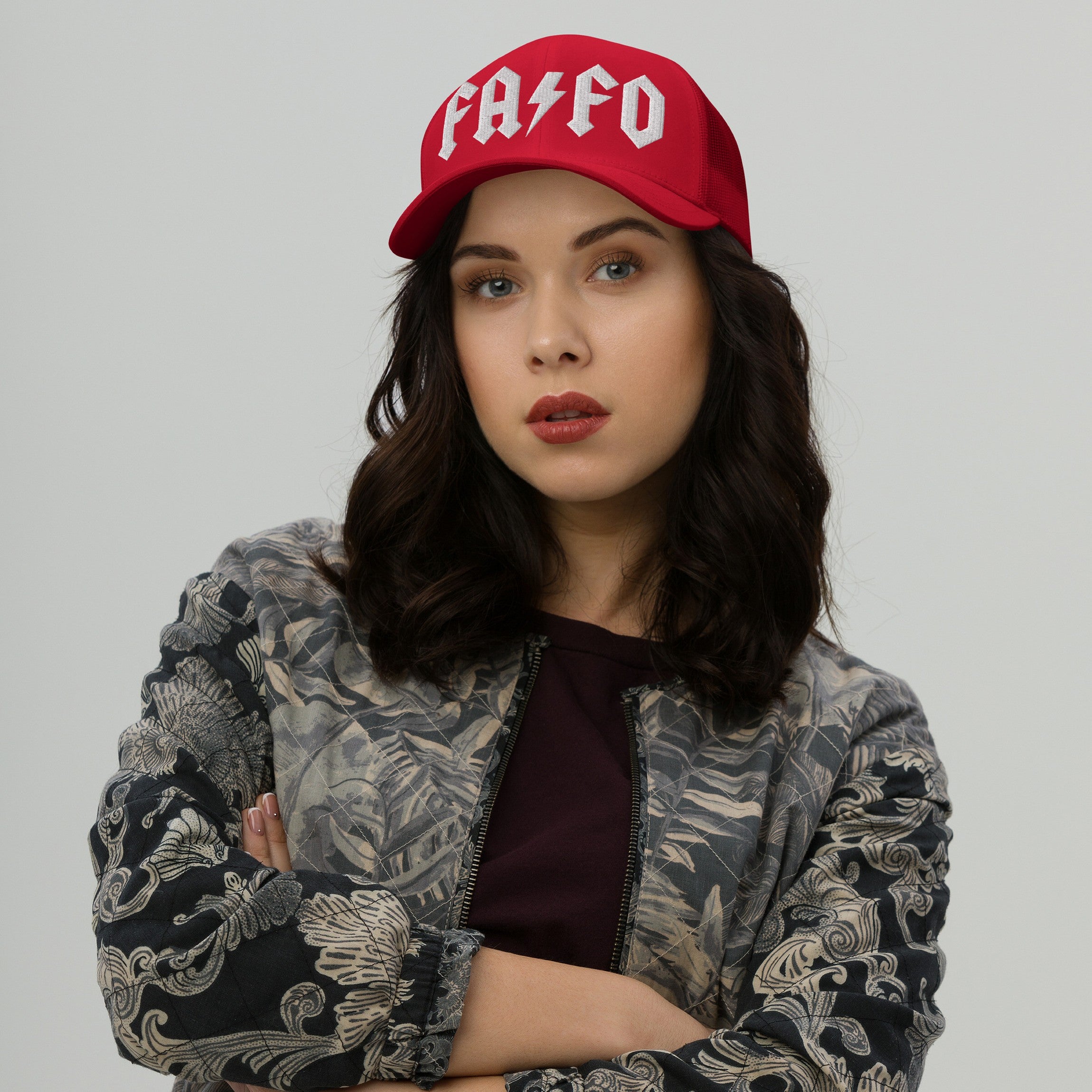 Young woman in a bold FAFO hat with rock-inspired lettering, paired with a floral bomber jacket, embodies defiance and resistance against fascism, reflecting a strong, confident stance.