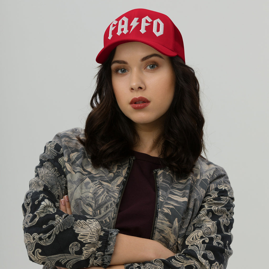 Young woman in a bold FAFO hat with rock-inspired lettering, paired with a floral bomber jacket, embodies defiance and resistance against fascism, reflecting a strong, confident stance.