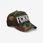FCKNZS Hat: A green/brown woodland camouflage baseball cap with bold white embroidered FCKN. on the front, symbolizing a strong anti-fascist message for visible protest and everyday wear.