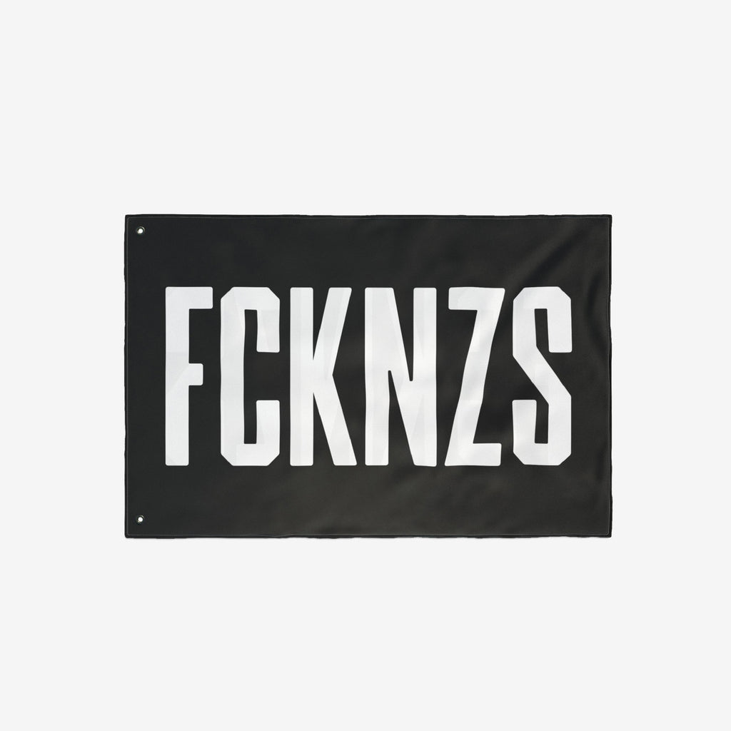 FCKNZS Flag - A bold black banner with FCKNZS in white block letters, featuring metal grommets for easy display. A visible anti-fascist statement for home or public spaces.