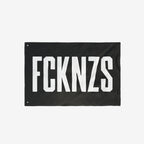 FCKNZS Flag - A bold black banner with FCKNZS in white block letters, featuring metal grommets for easy display. A visible anti-fascist statement for home or public spaces.