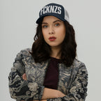 Young woman wears FCKNZS Hat, a dark trucker cap with bold white letters, embodying anti-fascist sentiment. Her confident pose complements the hat's statement, aligning with themes of equality and resistance.