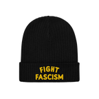 The Fight Fascism Hat features a black knit beanie with FIGHT FASCISM boldly embroidered in yellow on the cuff, making a clea