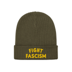 Olive-green ribbed knit beanie with FIGHT FASCISM embroidered in bold yellow letters on the cuff, representing anti-fascist a
