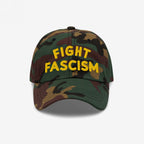 Camo-pattern Fight Fascism Hat with bold yellow FIGHT FASCISM slogan, designed for anti-fascist visibility. Ideal for marches or daily wear, embodying a message of resistance and equality.