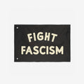 The Fight Fascism Flag features bold cream lettering on a black background, with metal grommets for hanging. Ideal for anti-fascist protests, it embodies a strong stance for equality and justice.