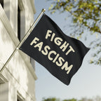 Fight Fascism Flag displayed outside, featuring bold cream text on a black background. Designed for equality advocates and anti-fascist protests, perfect for public demonstrations or personal expression.