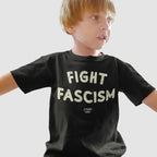 Young boy wearing a Fight Fascism T-shirt with bold off-white distressed letters. This anti-fascist design reflects activism and resistance, ideal for those who actively oppose hate and support equality.