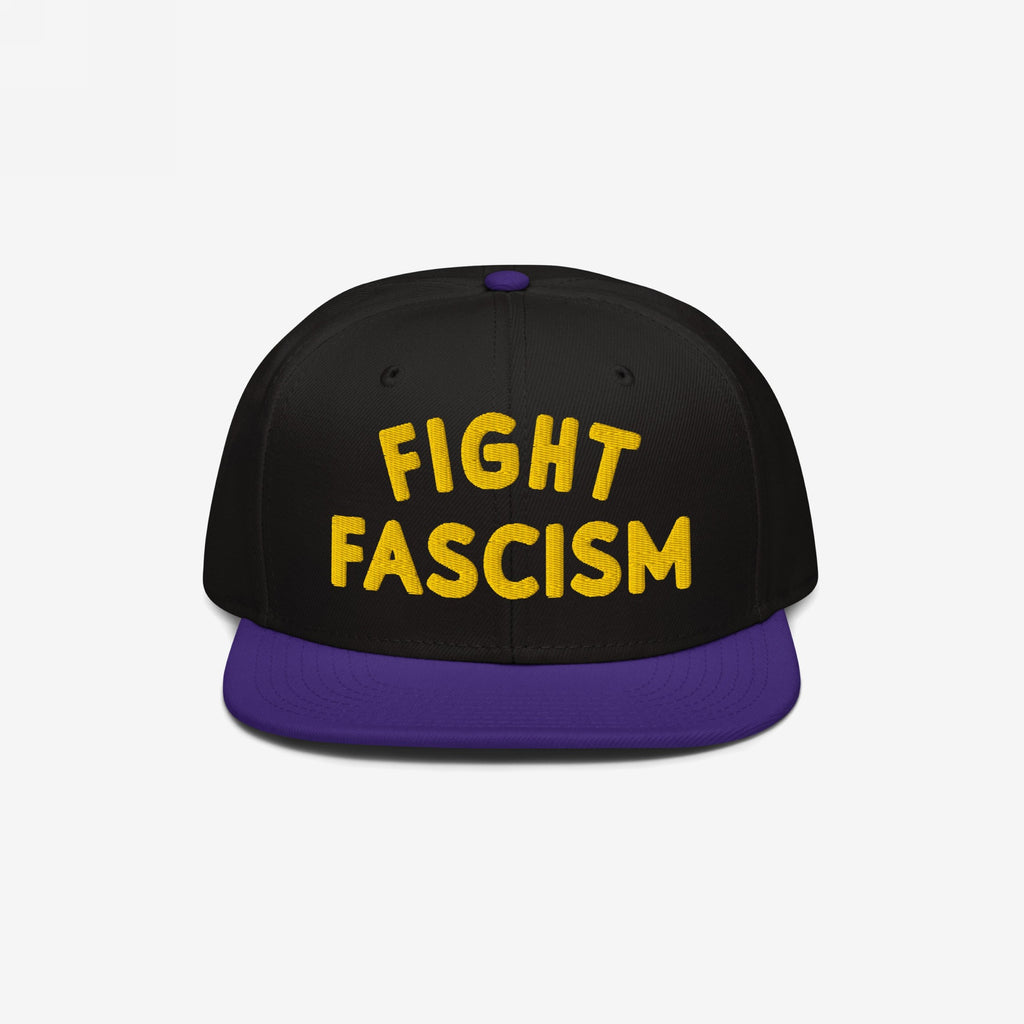 Fight Fascism Hat features bold yellow embroidery on a black crown, with a purple brim. Designed for visibility, this snapback cap makes a statement against fascism, supporting equality and inclusivity.