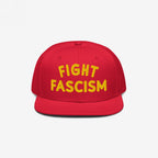 Fight Fascism Hat featuring a red snapback design with FIGHT FASCISM boldly embroidered in yellow. This statement piece supports anti-fascist causes, perfect for visible protest and daily wear.