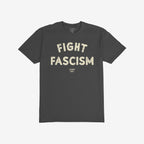 Dark charcoal-gray Fight Fascism T-shirt with distressed off-white text, advocating against fascism. Brand name appears below. Laid flat on a white background, embodying activism and social justice ethos.