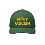 Fight Fascism Hat: Green trucker cap with yellow FIGHT FASCISM embroidery, featuring a curved brim and mesh back. Ideal for p