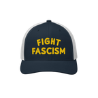 Navy-blue and white mesh trucker cap with yellow FIGHT FASCISM embroidery, embodying anti-fascist protest spirit. Ideal for v