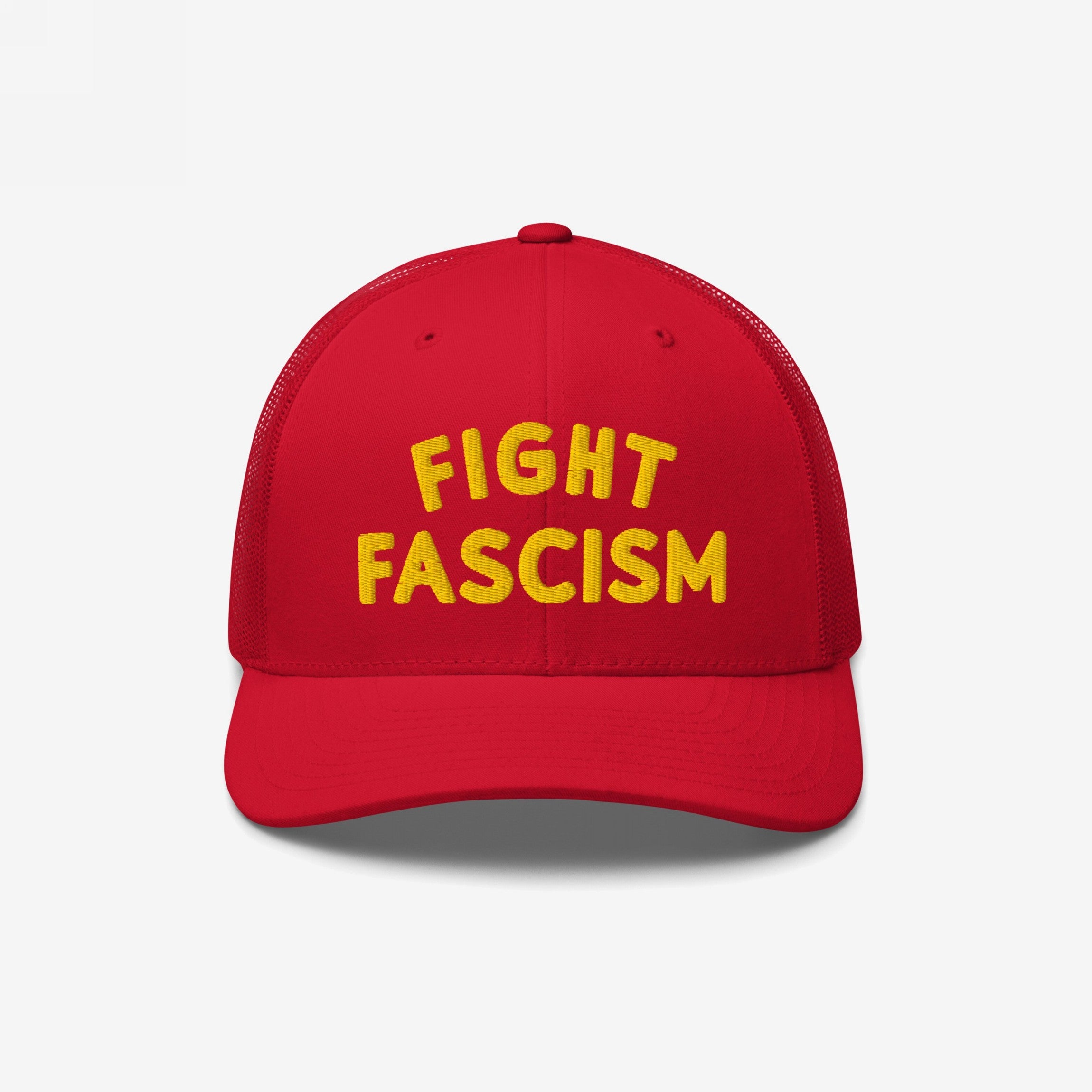 Red mesh-back trucker cap with bold yellow FIGHT FASCISM embroidery on the front, embodying a strong anti-fascist message for visibility and activism in everyday settings.