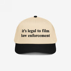 Film The Police Hat featuring a light tan front and black bill, boldly stating “it’s legal to film law enforcement.” A statement piece reflecting the fight for police accountability and rights awareness.