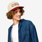 Young man in a denim shirt wearing the Film The Police Hat, a two-tone baseball cap with it’s legal to film law enforcement slogan, reflecting protest gear for police accountability.